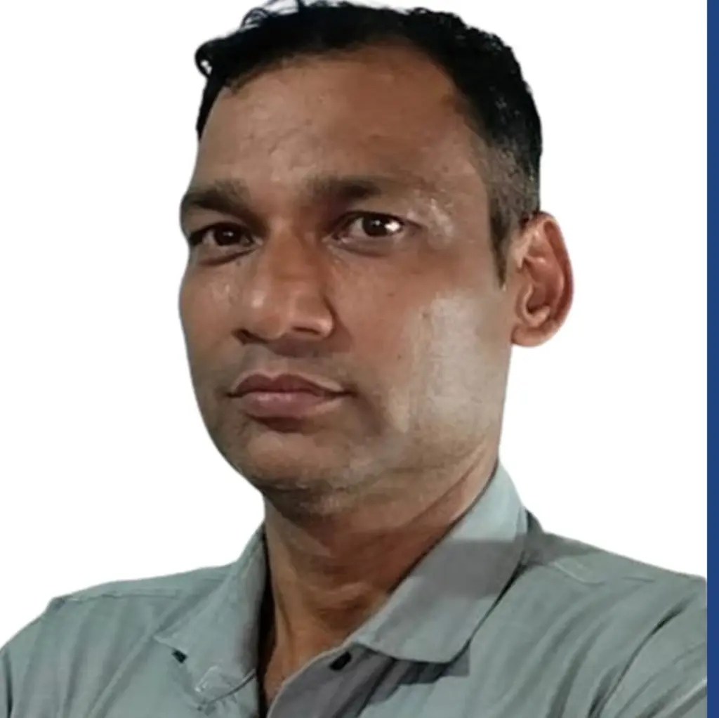A man wearing a light grey shirt looks slightly to the side against a plain white background.