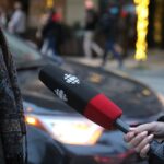 A person being interviewed on a Vancouver street, holding a microphone.